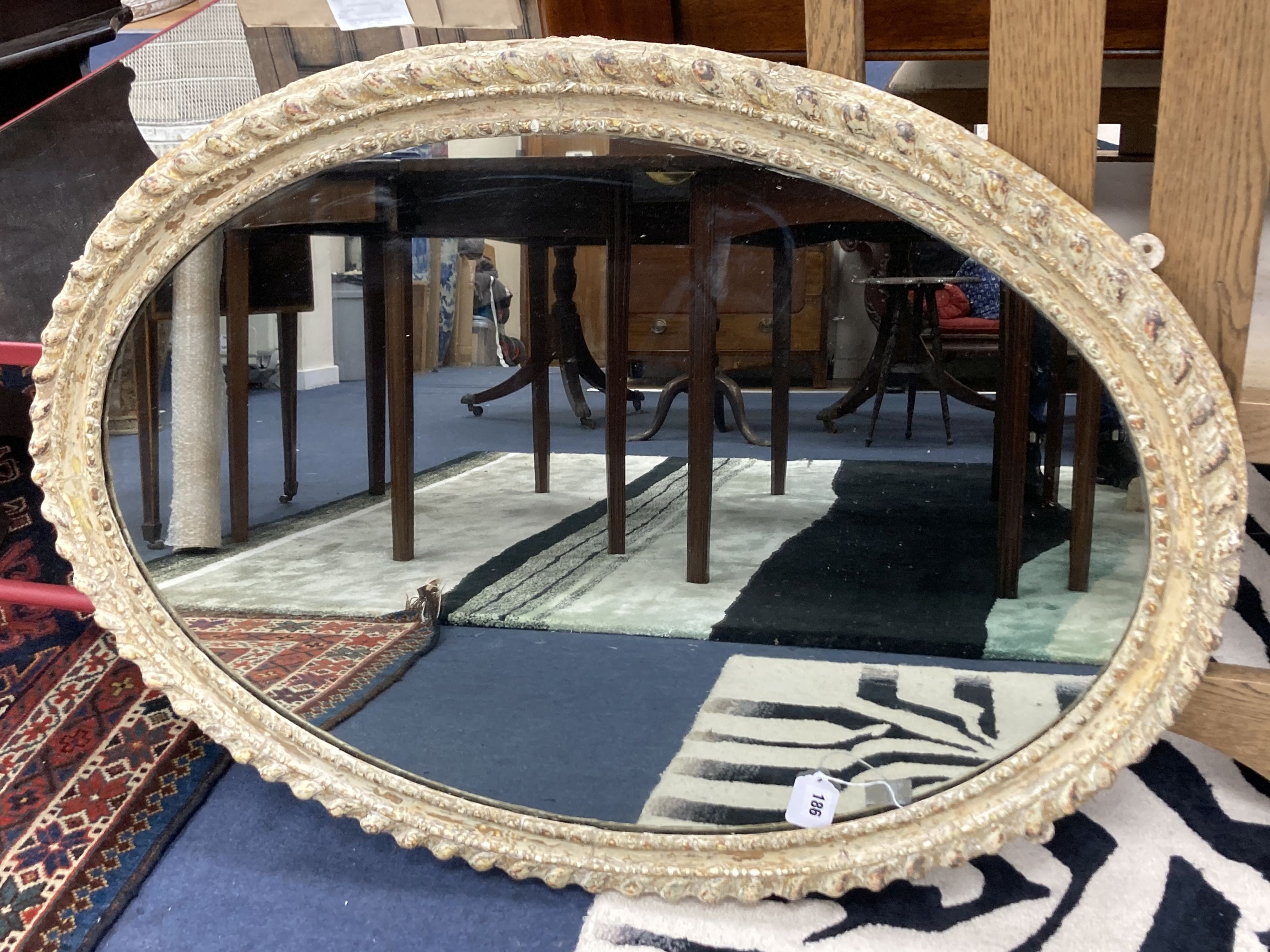 A decorative painted oval wall mirror, 96 x 70 cms.